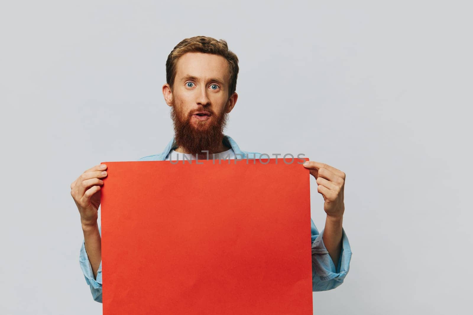 Portrait of an adult male on a gray background with a red piece of paper for your design and text, layout, copy space, space for text. High quality photo