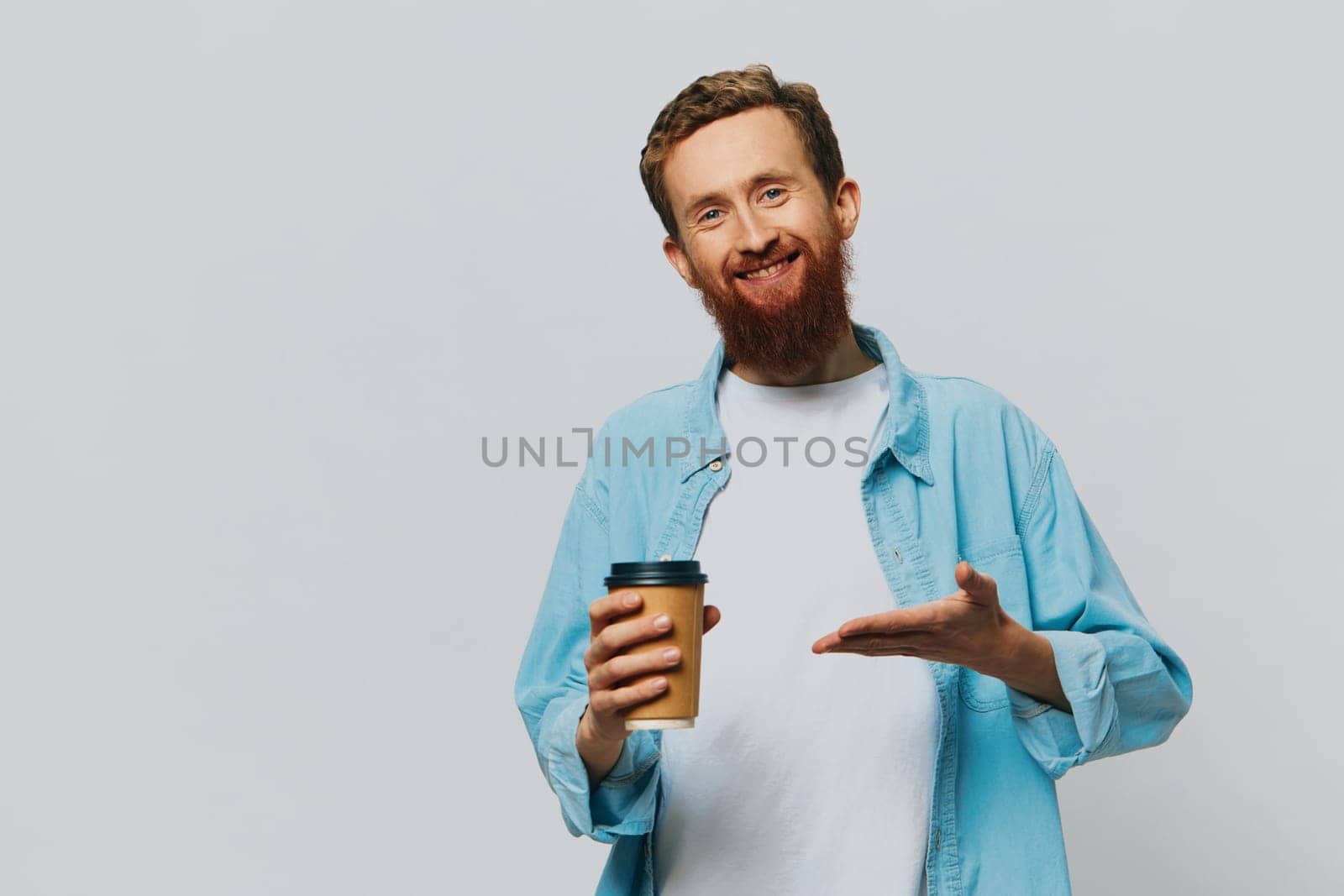 Man hipster with a cup of coffee with a smile on a gray background in a blue shirt and white t-shirt. High quality photo