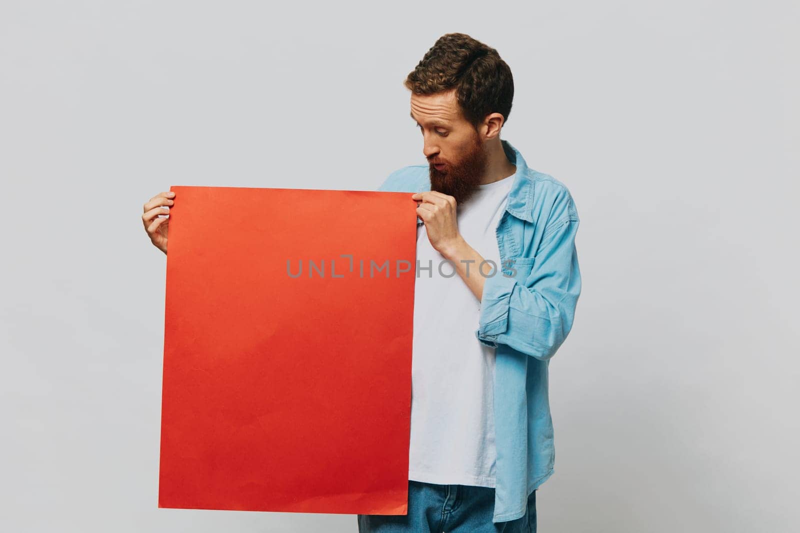 Portrait of an adult male on a gray background with a red piece of paper for your design and text, layout, copy space, space for text by SHOTPRIME