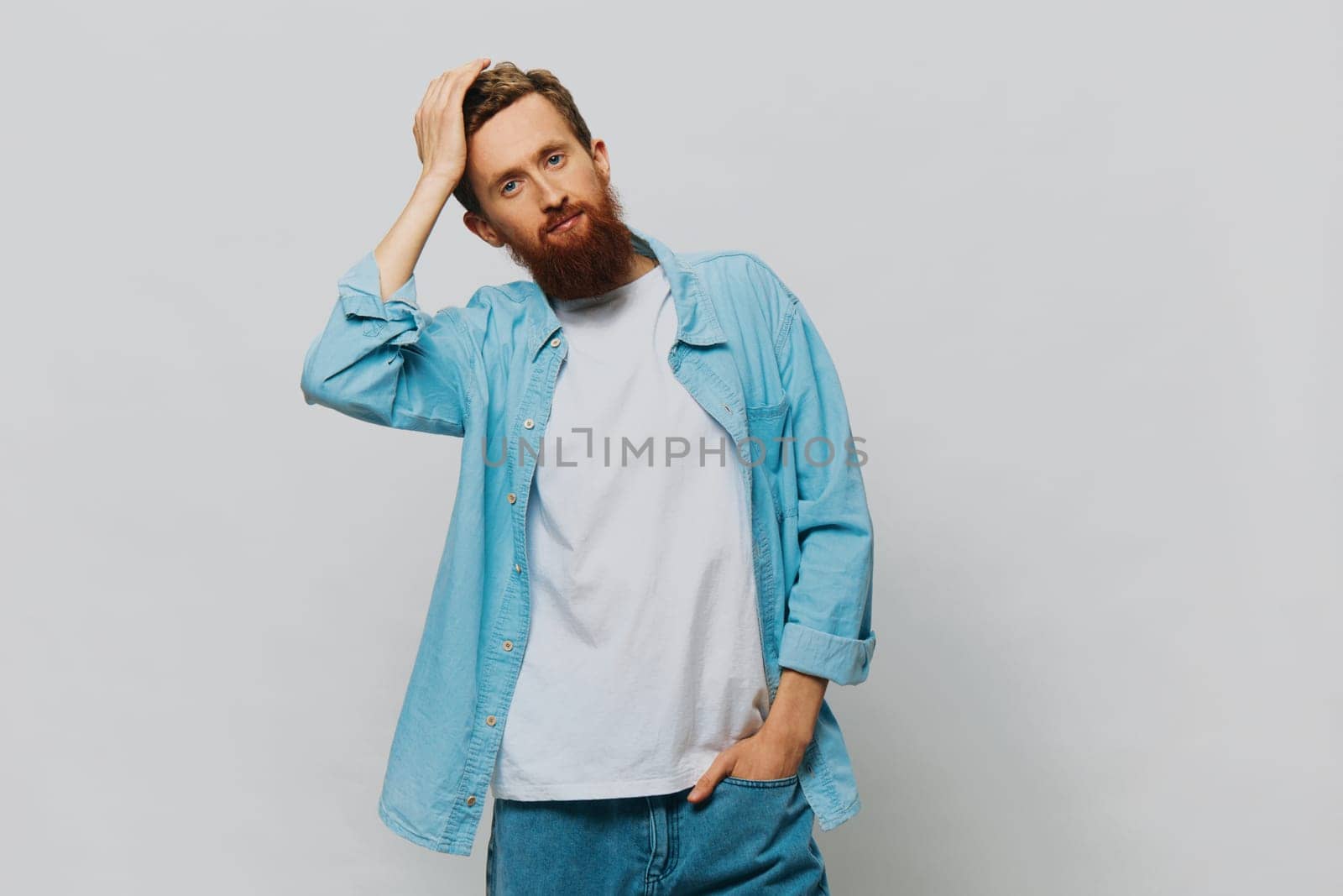 Male hipster portrait smile on gray background in blue shirt and white t-shirt, portrait of a man with a beard by SHOTPRIME