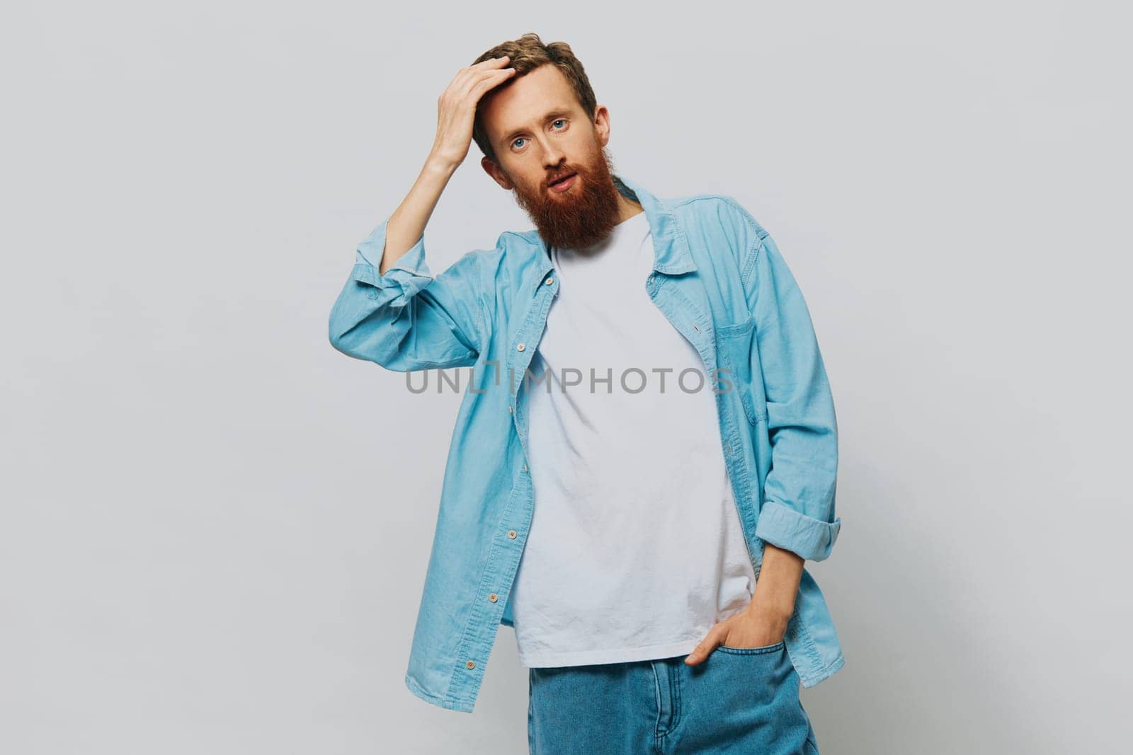 Male hipster portrait smile on gray background in blue shirt and white t-shirt, portrait of a man with a beard. High quality photo