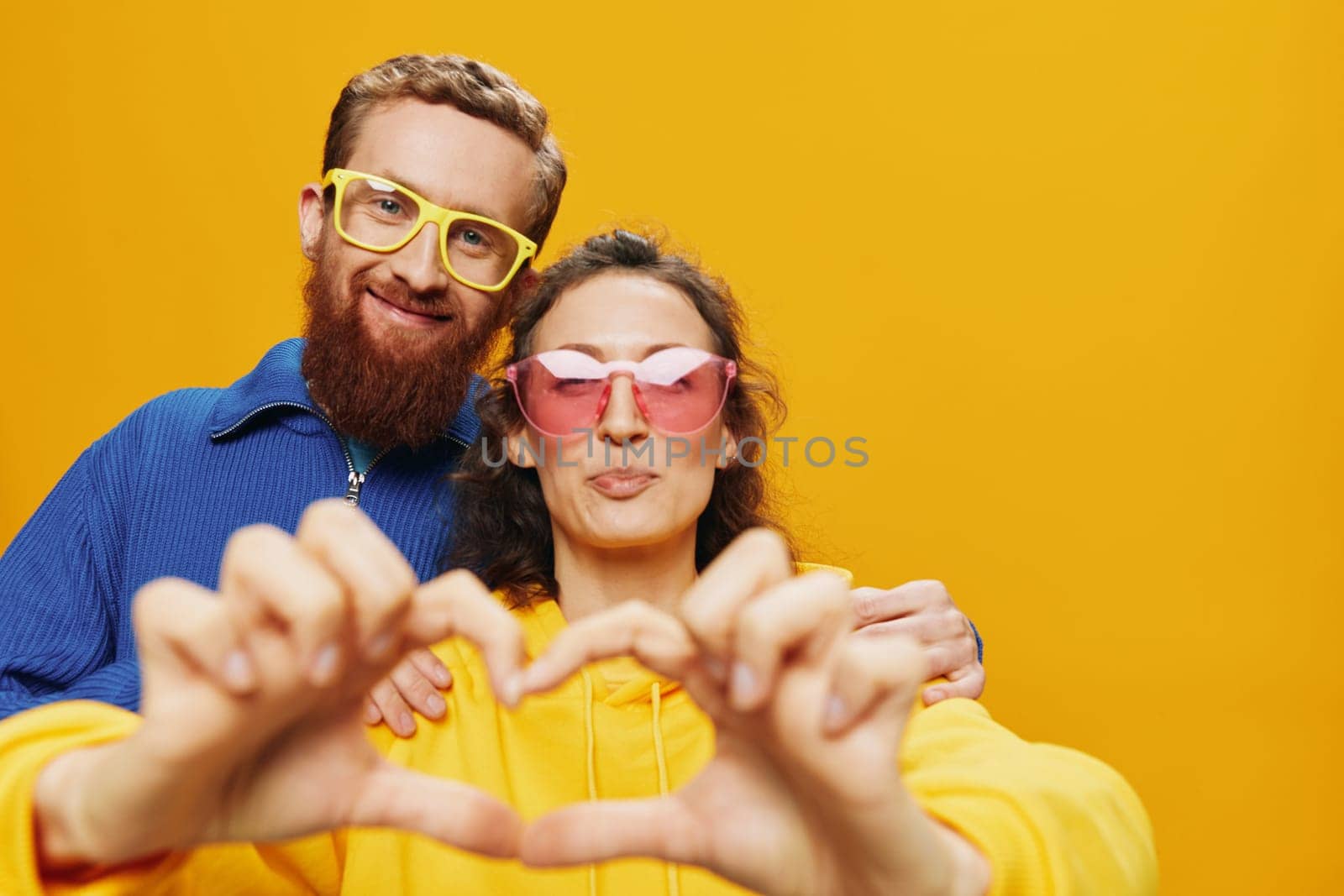 Man and woman couple smiling cheerfully and crooked with glasses, on yellow background, symbols signs and hand gestures, family shoot, newlyweds. by SHOTPRIME