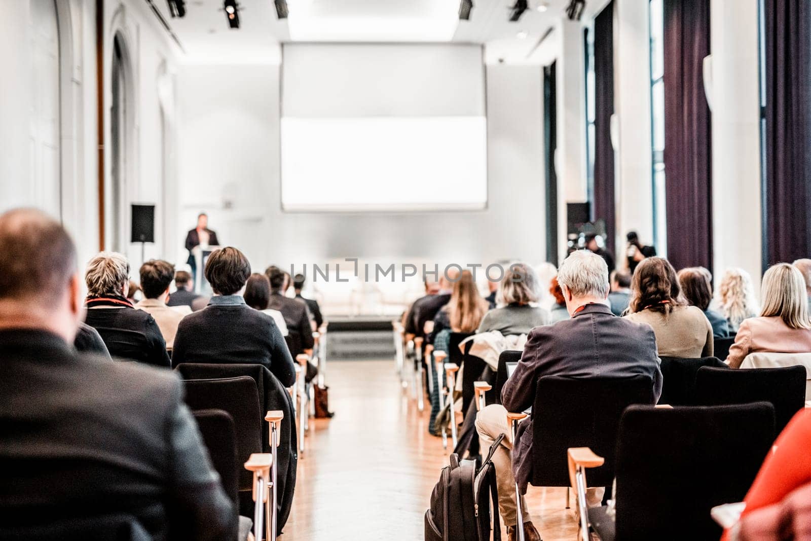 Speaker giving a talk in conference hall at business event. Rear view of unrecognizable people in audience at the conference hall. Business and entrepreneurship concept. by kasto