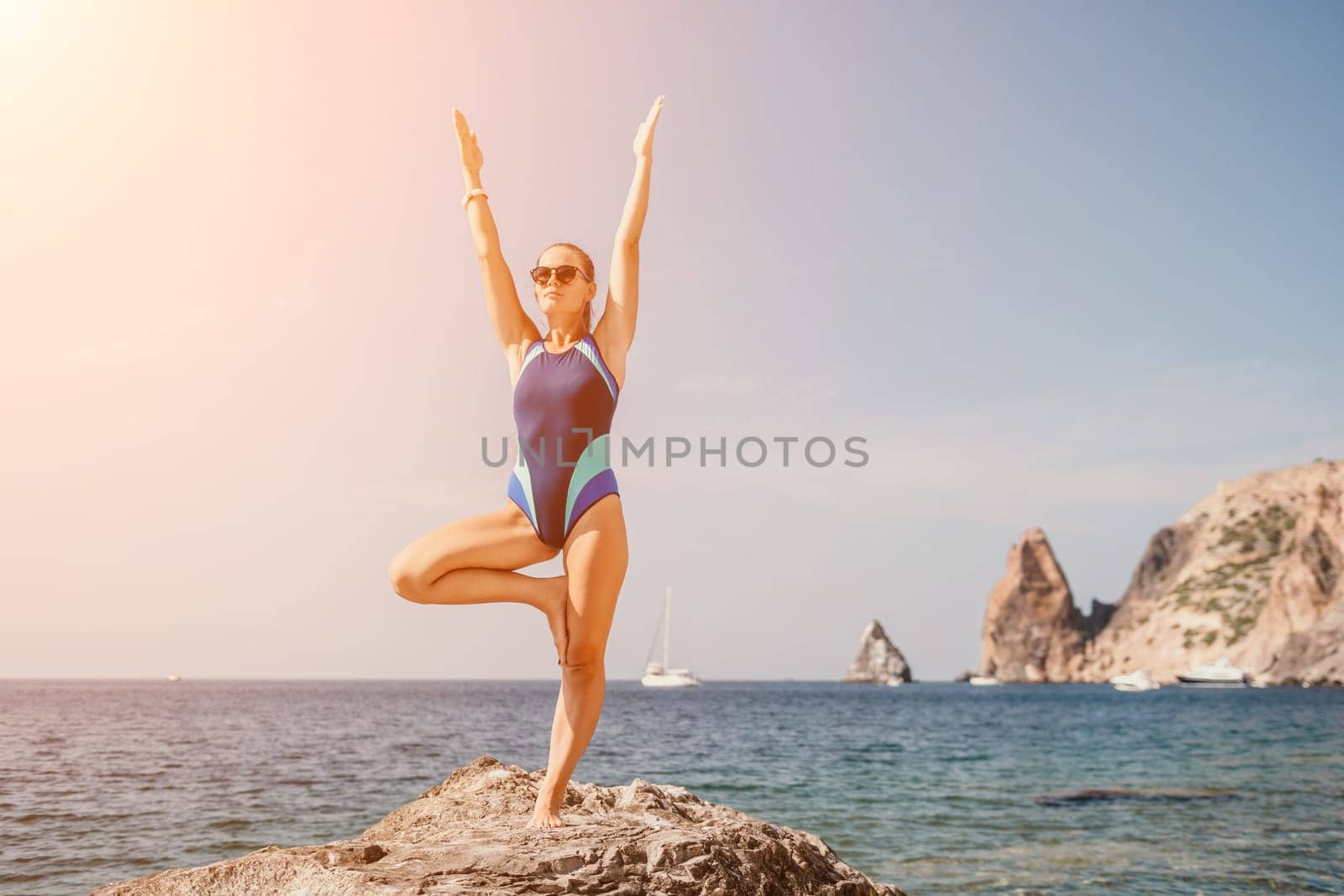 Woman sea yoga. Back view of free calm happy satisfied woman with long hair standing on top rock with yoga position against of sky by the sea. Healthy lifestyle outdoors in nature, fitness concept.