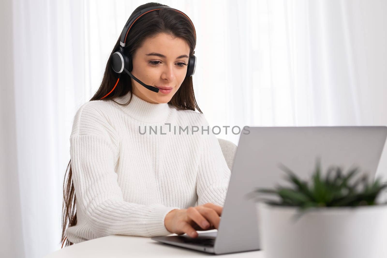 Young woman in headset working online via laptop. Psychological help or remote consultant online via call center