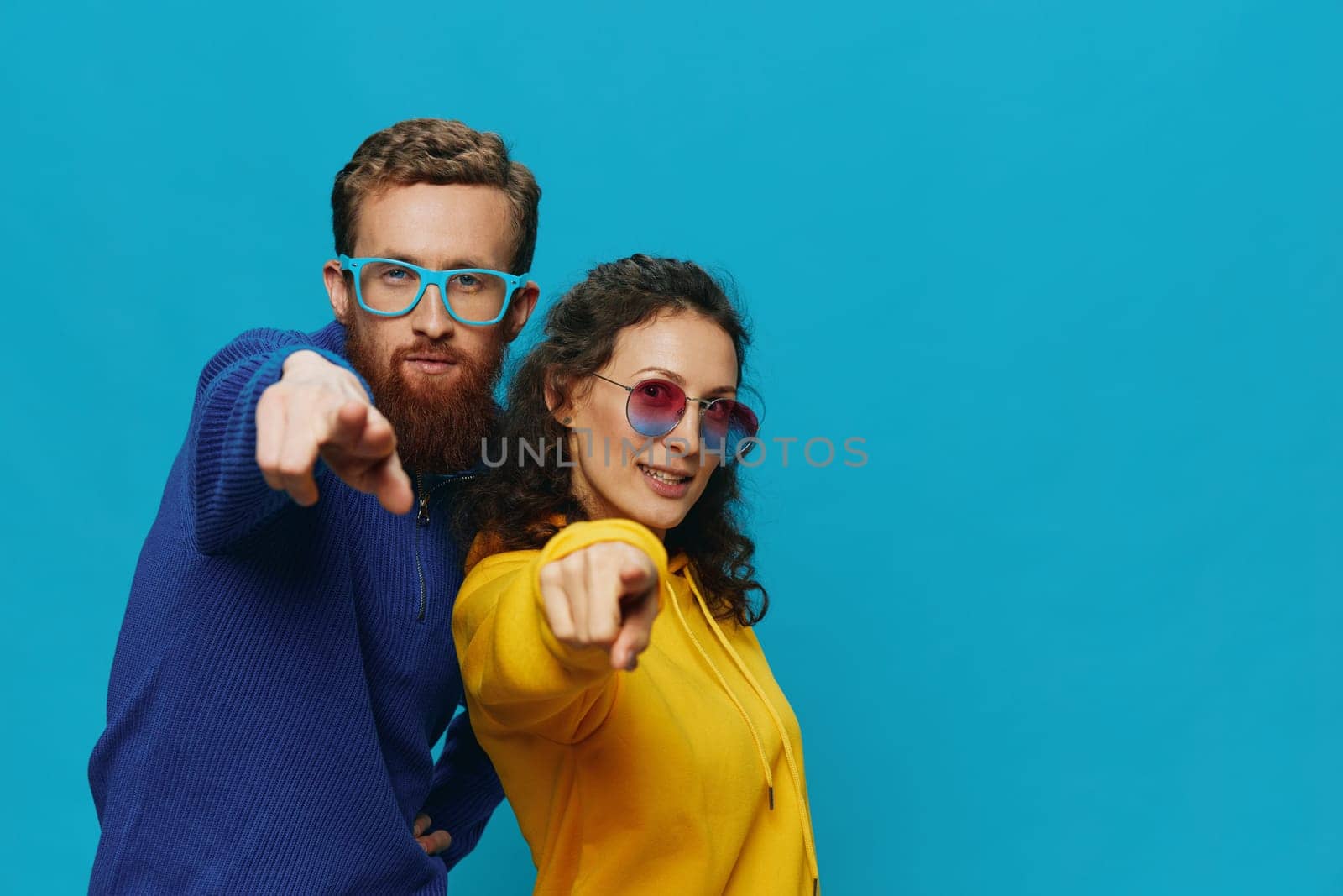 A woman and a man fun couple cranking and showing signs with their hands smiling cheerfully, on a blue background, The concept of a real relationship in a family. by SHOTPRIME