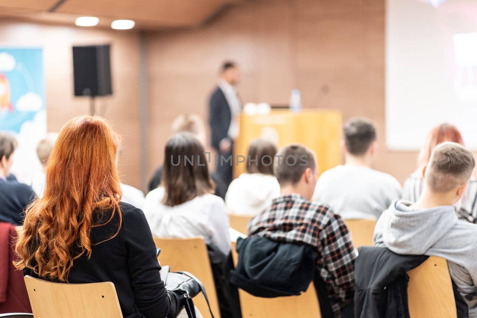 Speaker giving a talk in conference hall at business event. Rear view of unrecognizable people in audience at the conference hall. Business and entrepreneurship concept. by kasto