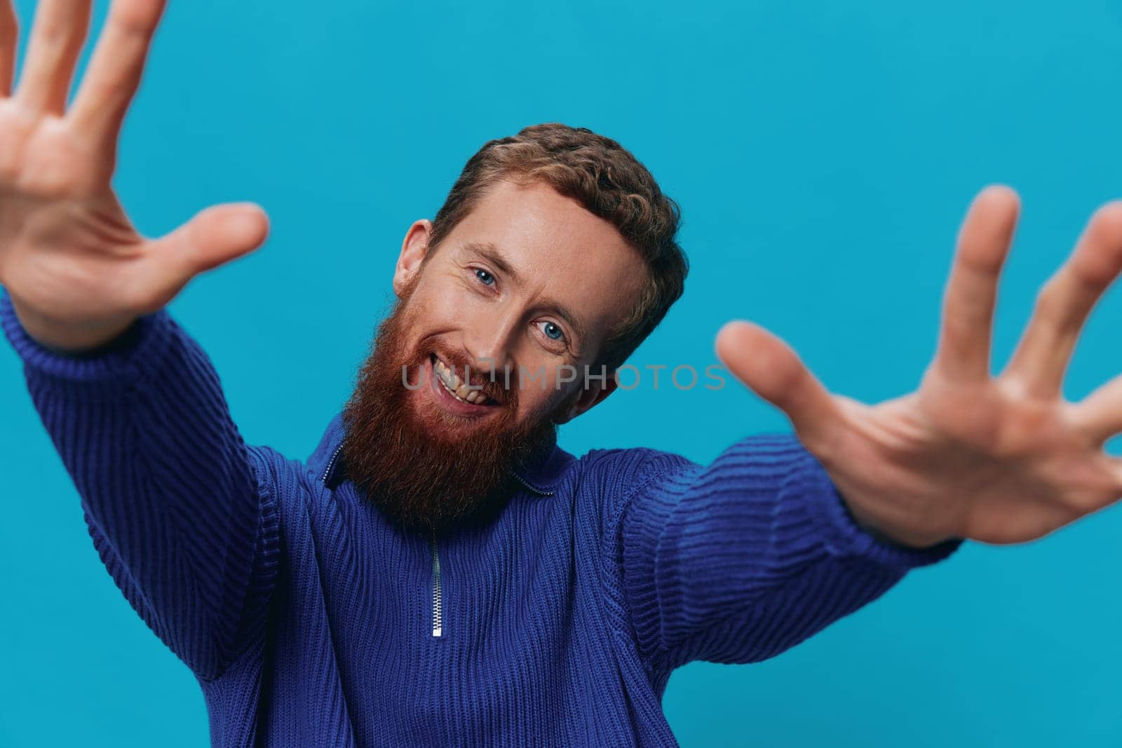 Portrait of a man in a sweater smile and happiness, hand signs and symbols, on a blue background. Lifestyle positive, copy place. by SHOTPRIME
