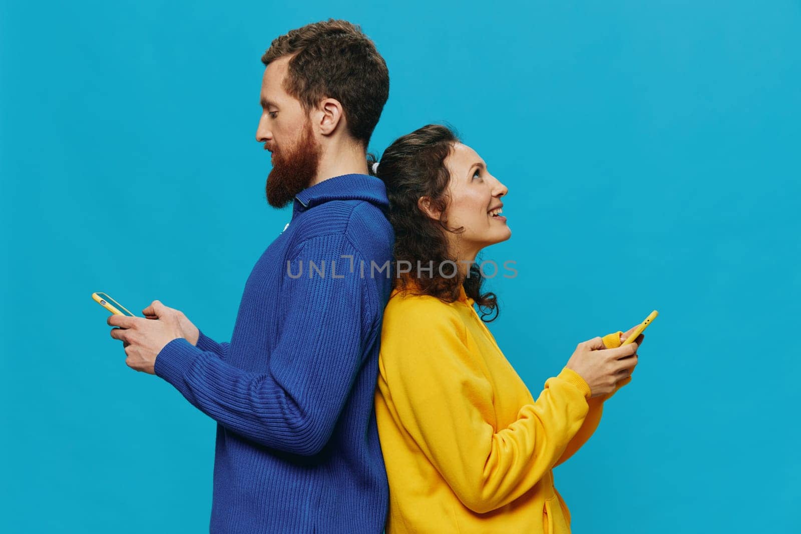 Woman and man cheerful couple with phones in their hands crooked smile cheerful, on blue background. The concept of real family relationships, talking on the phone, work online. High quality photo