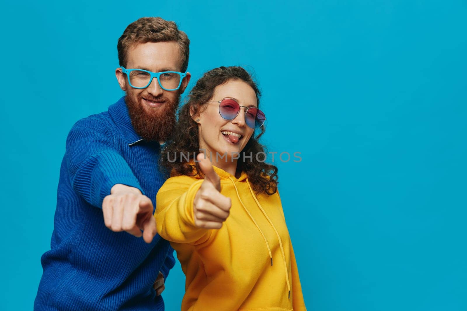 A woman and a man fun couple cranking and showing signs with their hands smiling cheerfully, on a blue background, The concept of a real relationship in a family. High quality photo