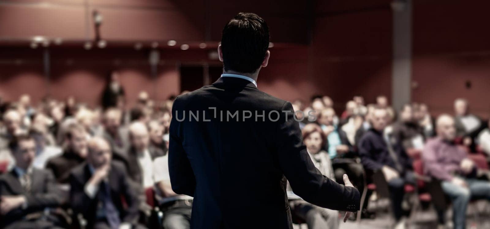 Speaker giving a talk on corporate business conference. Unrecognizable people in audience at conference hall. Business and Entrepreneurship event.