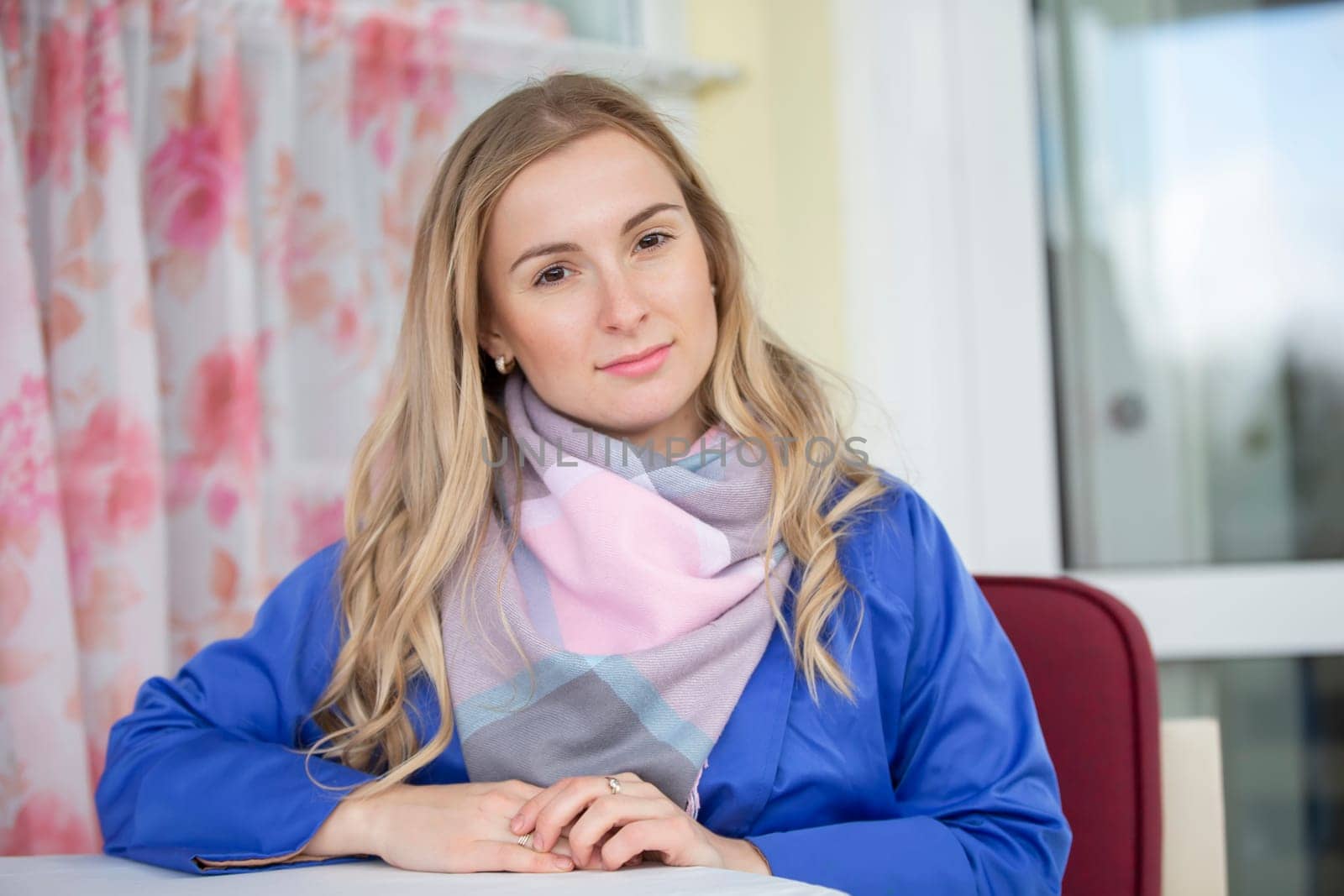 Portrait of a beautiful young woman at a street cafe table in a blue jacket.