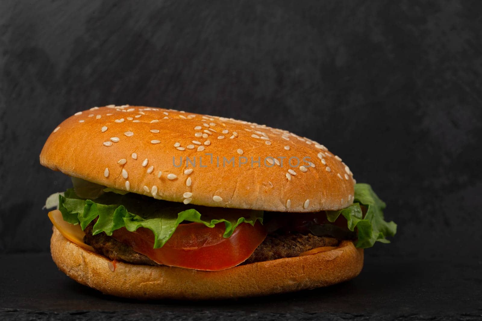 Classic hamburger close-up on a black background. by Sviatlana