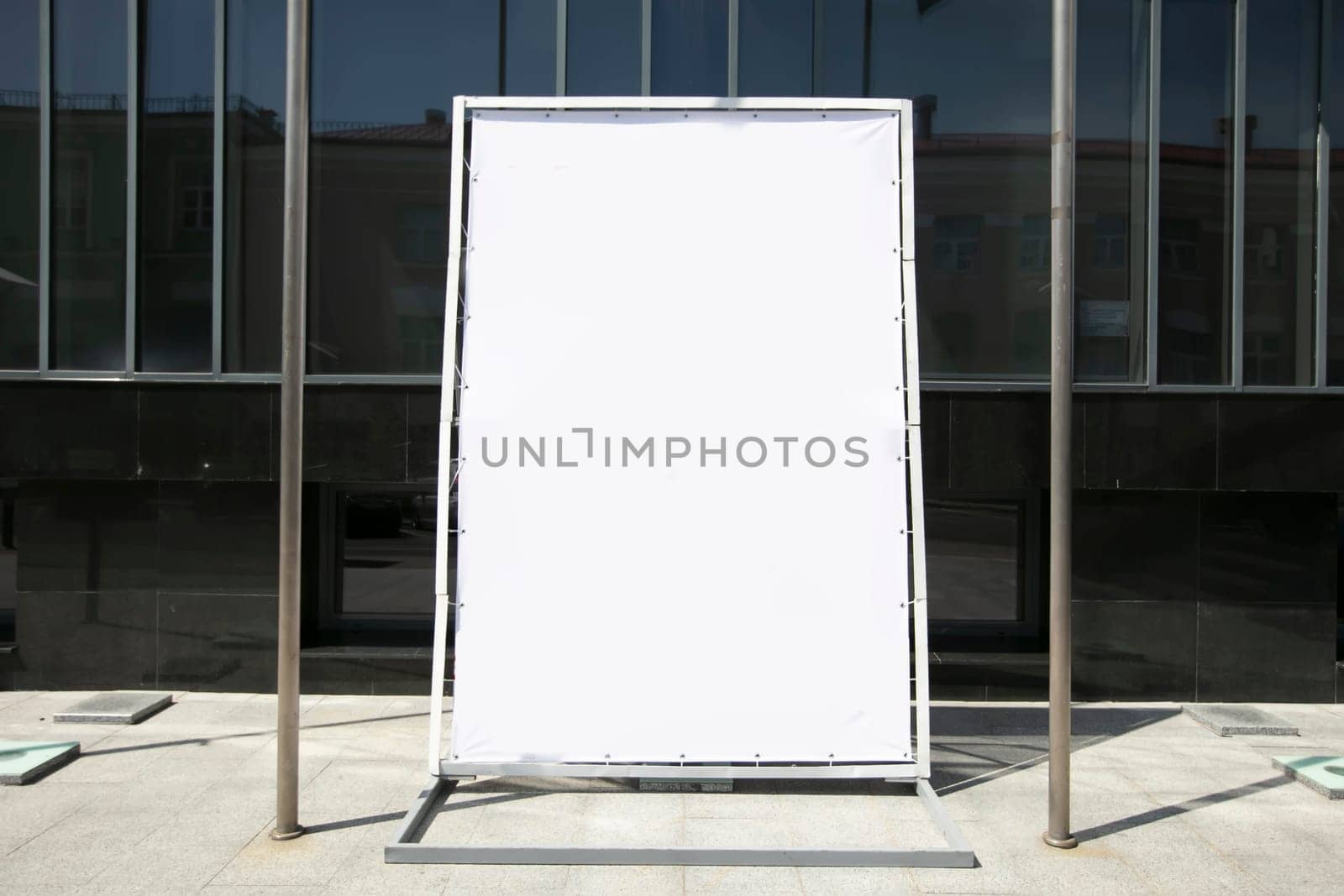 An empty advertising banner stands on a city street. by Sviatlana
