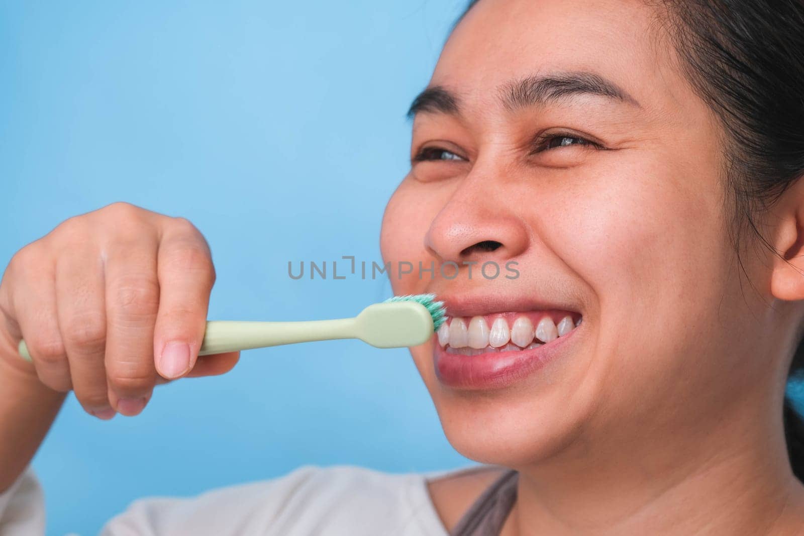 Happy Asian woman taking care of her teeth and holding a toothbrush. Young lady brushing her teeth. dental care and oral hygiene concept. by TEERASAK