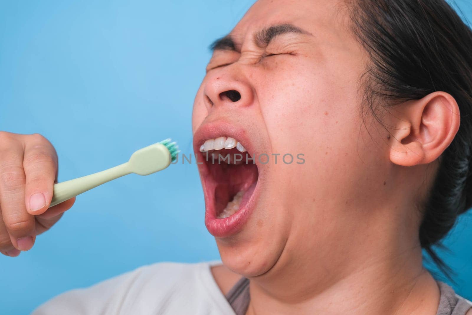 Yawn woman wake up with tooth brush on blue background. Oral care concept.