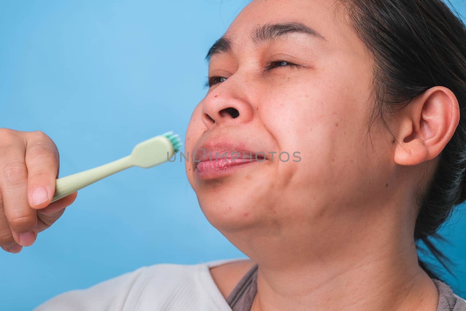 Yawn woman wake up with tooth brush on blue background. Oral care concept. by TEERASAK