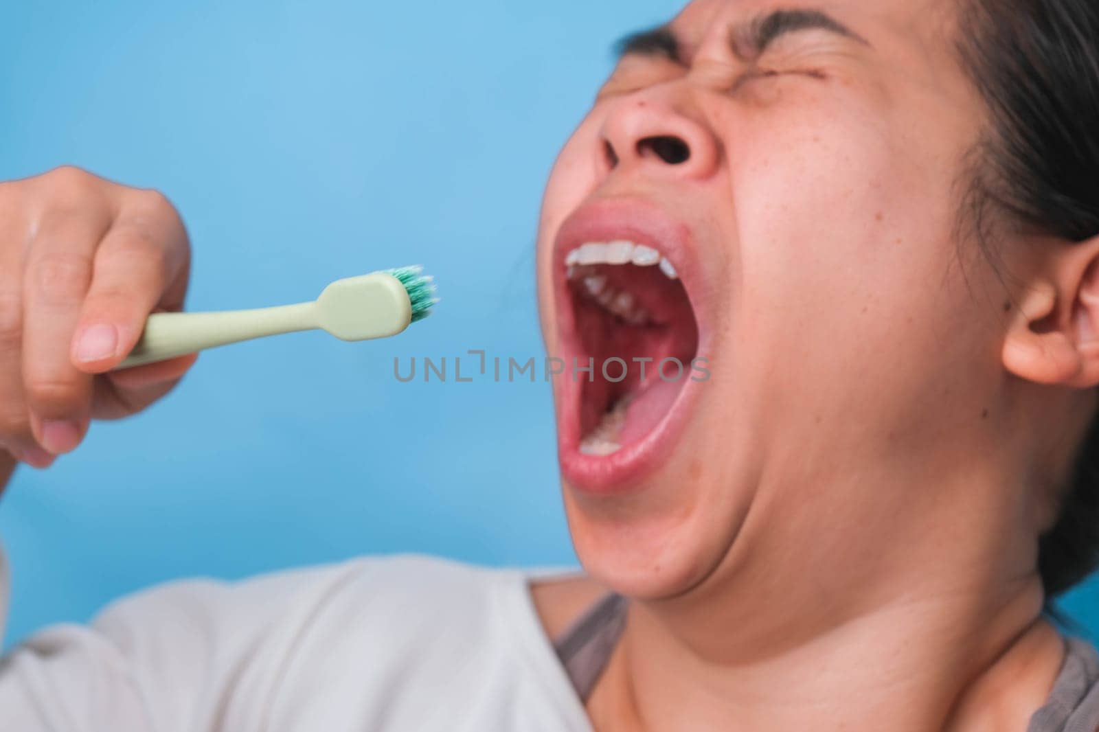 Yawn woman wake up with tooth brush on blue background. Oral care concept.