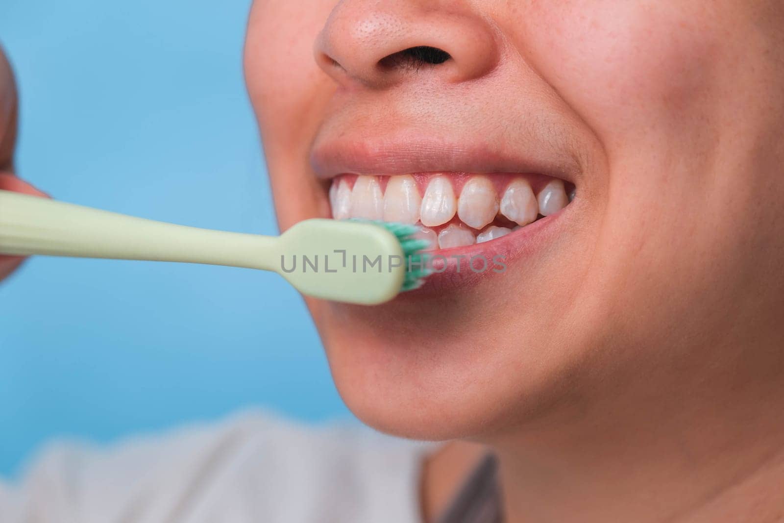Happy Asian woman taking care of her teeth and holding a toothbrush. Young lady brushing her teeth. dental care and oral hygiene concept. by TEERASAK