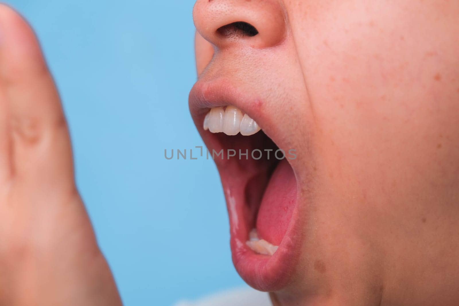 Woman covering her mouth to smell the bad breath. Young lady checking breath with her hands. Oral health problems or dental care concept.