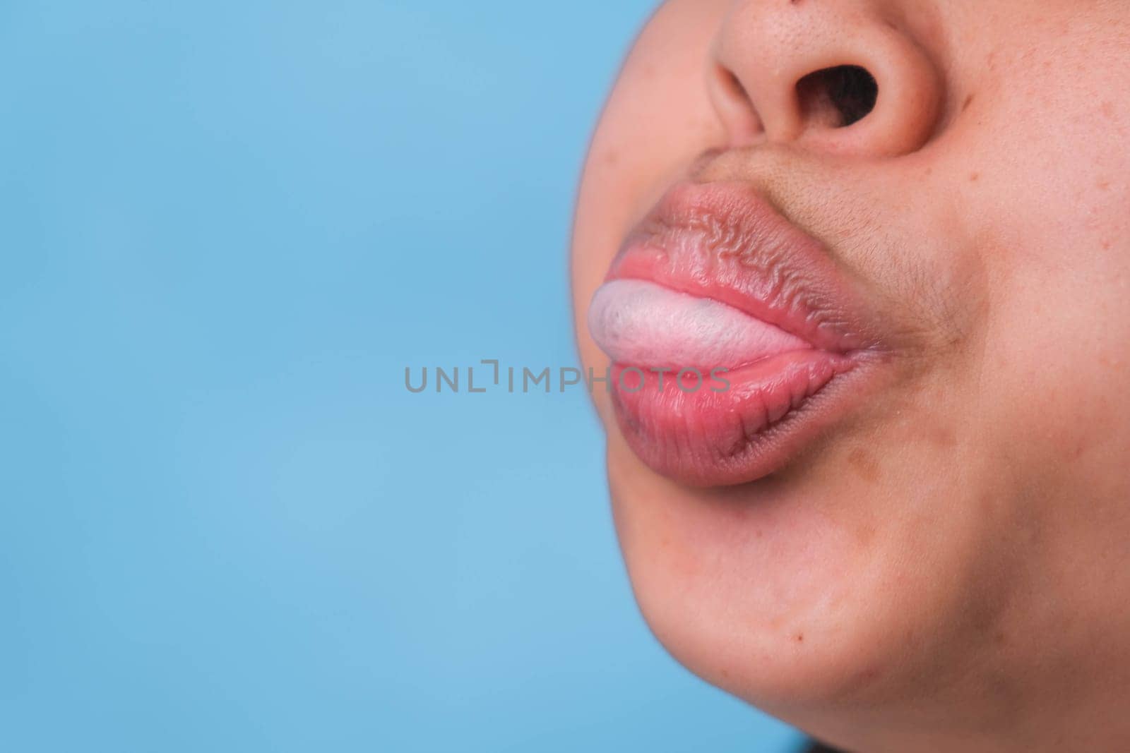 Young woman chewing gum and blowing bubble gum on blue background.