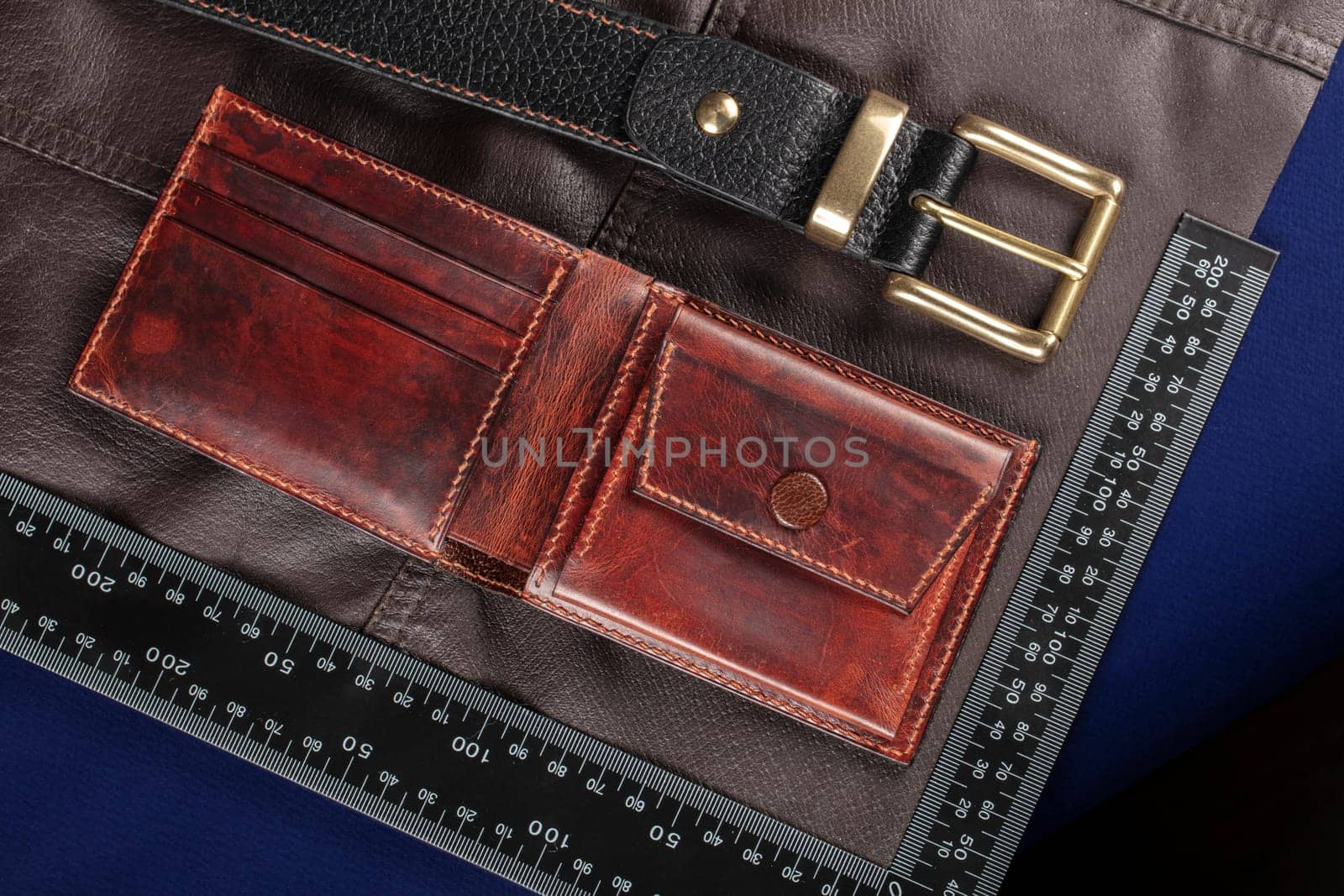 Leather goods purse and belt against the background of a ruler for cutting and sewing.