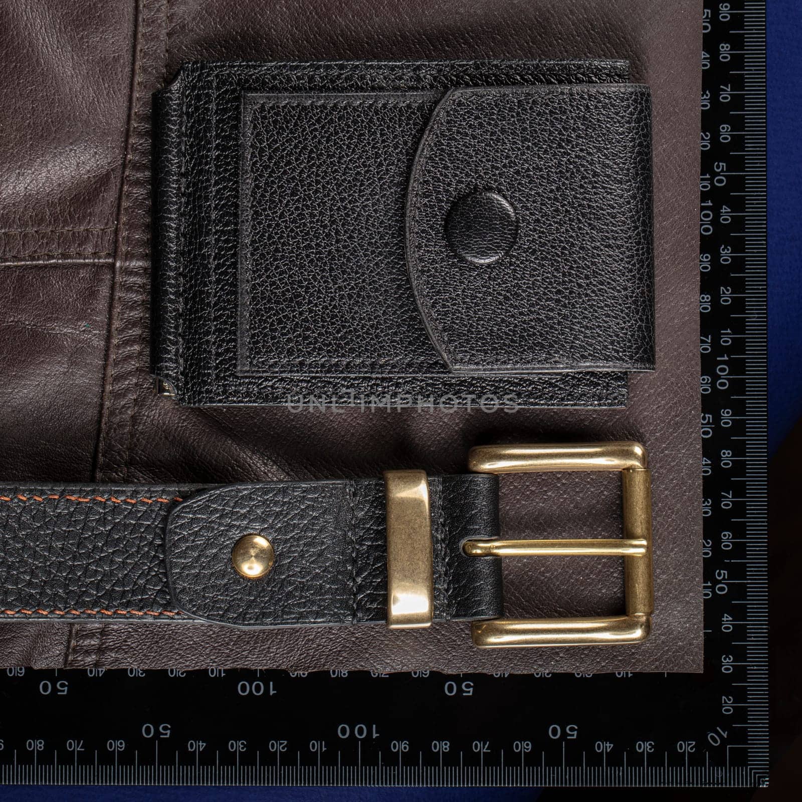 Leather goods purse and belt against the background of a ruler for cutting and sewing.