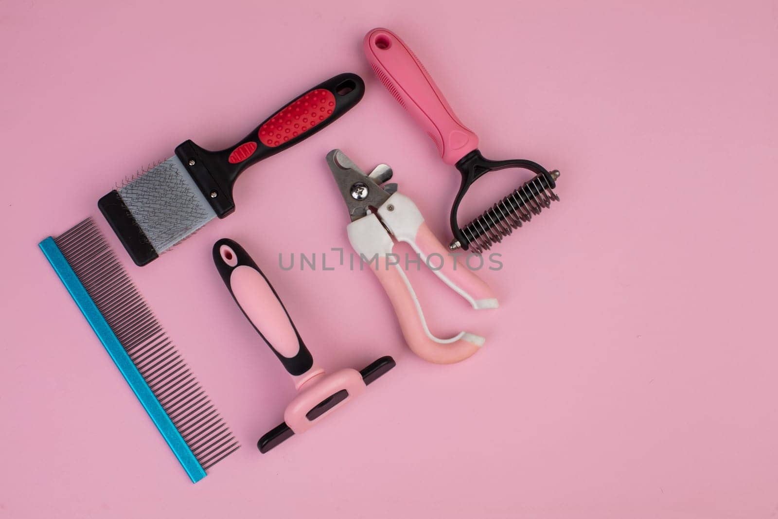 Tool for the groomer on a pink background. Dog grooming accessories. Combs and brushes for animals. View from above