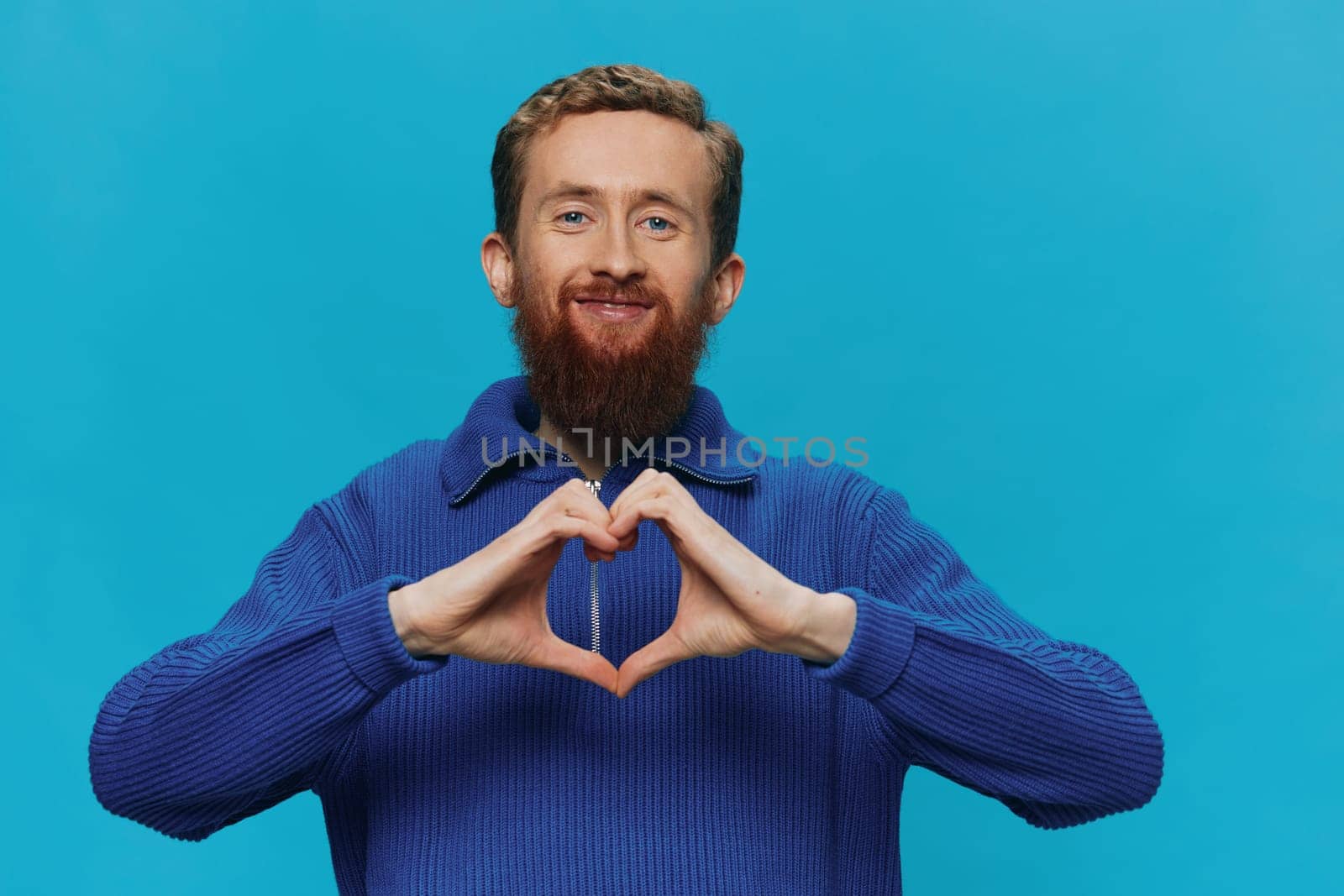 Portrait of a man in a sweater smile and happiness, hand signs and symbols, on a blue background. Lifestyle positive, copy place. High quality photo
