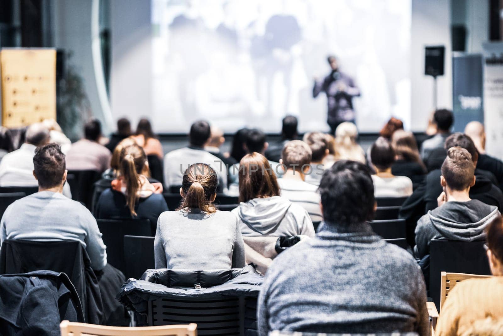 Speaker giving a talk in conference hall at business event. Audience at the conference hall. Business and Entrepreneurship concept. Focus on unrecognizable people in audience.