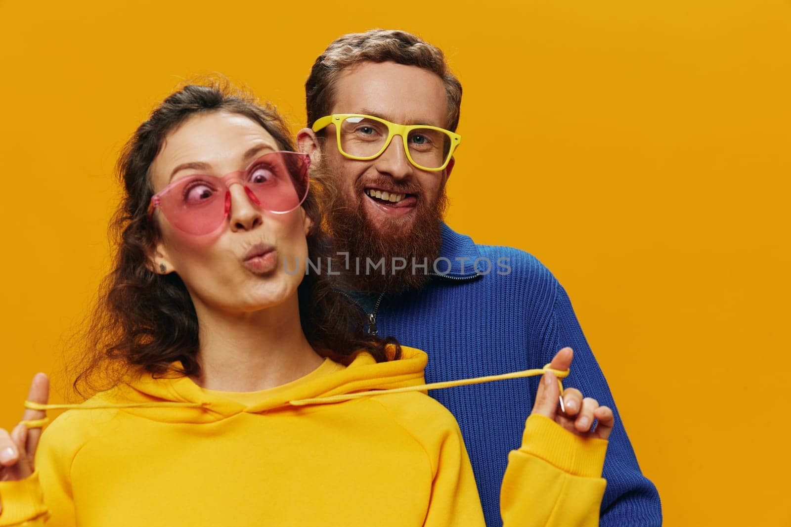 Man and woman couple smiling cheerfully and crooked with glasses, on yellow background, symbols signs and hand gestures, family shoot, newlyweds. by SHOTPRIME