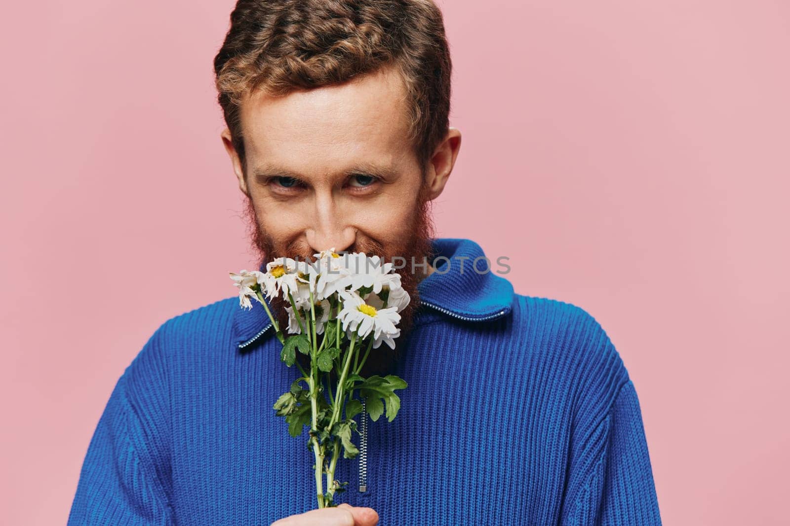 Portrait of a funny man smiling with a bouquet of flowers daisies on pink isolated background, copy place. Holiday concept and congratulations, Valentine's Day, Women's Day. High quality photo