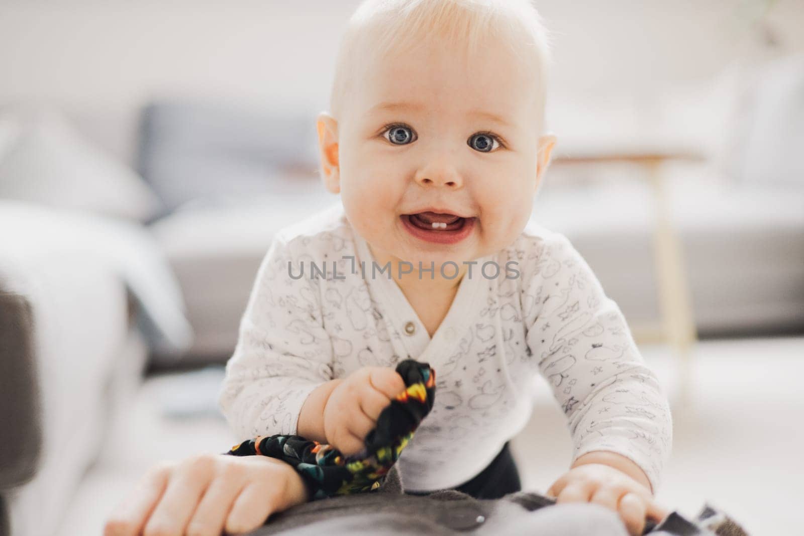 Cute infant baby boy playing, crawling and standing upat home. Baby playing at home.