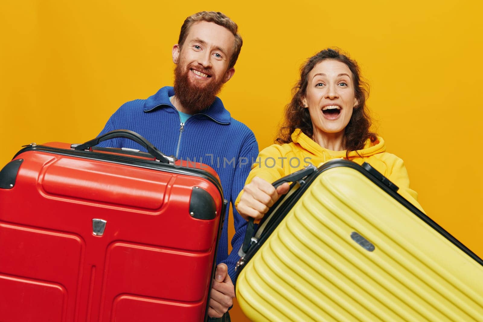 Woman and man smiling, suitcases in hand with yellow and red suitcase smiling merrily and crooked, yellow background, going on a trip, family vacation trip, newlyweds. by SHOTPRIME