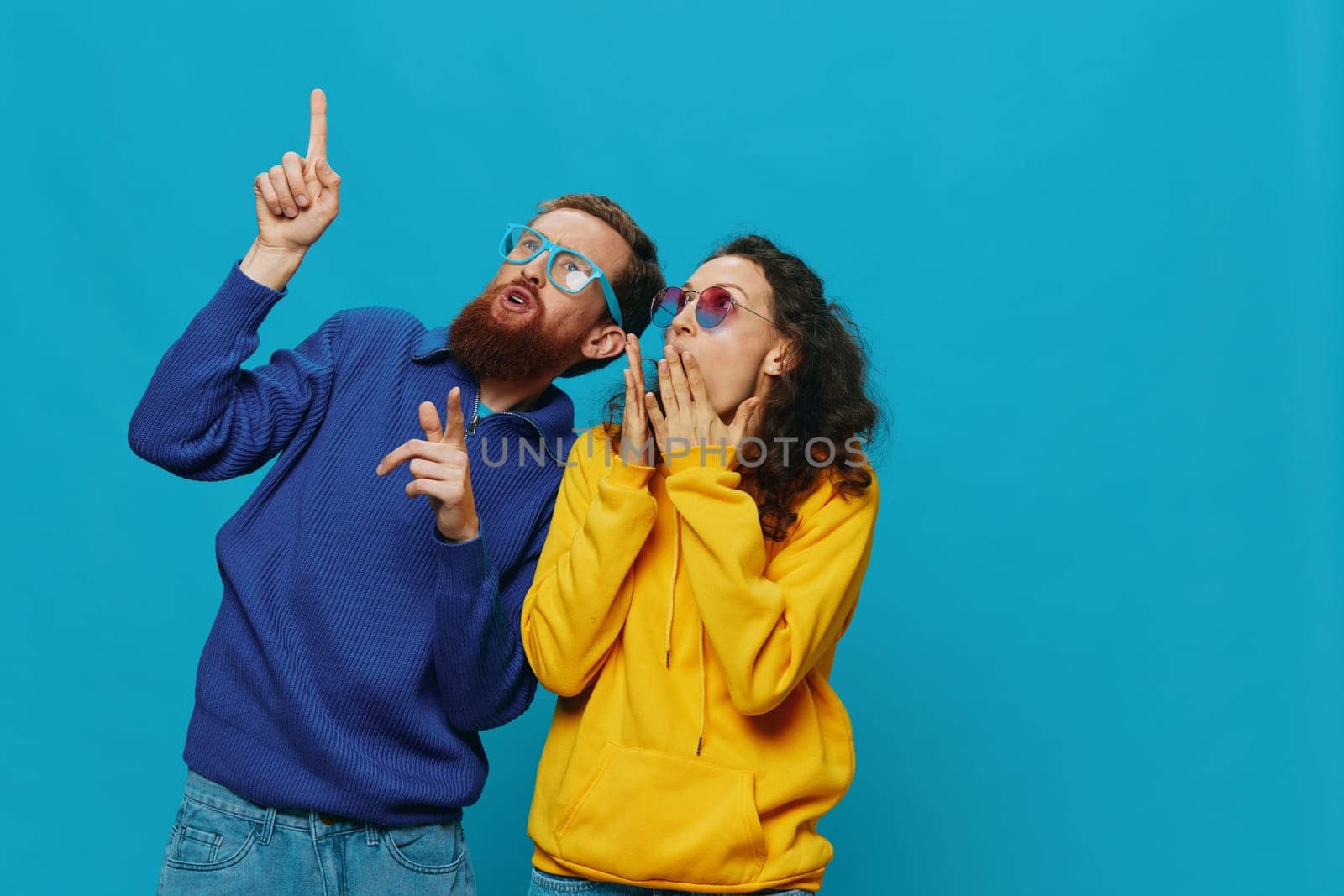 A woman and a man fun couple cranking and showing signs with their hands smiling cheerfully, on a blue background, The concept of a real relationship in a family. High quality photo