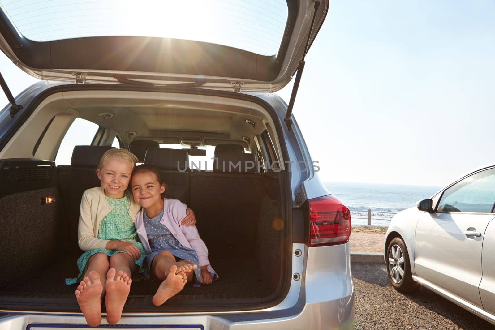 Travel buddies. two little girls sitting in the trunk of a car