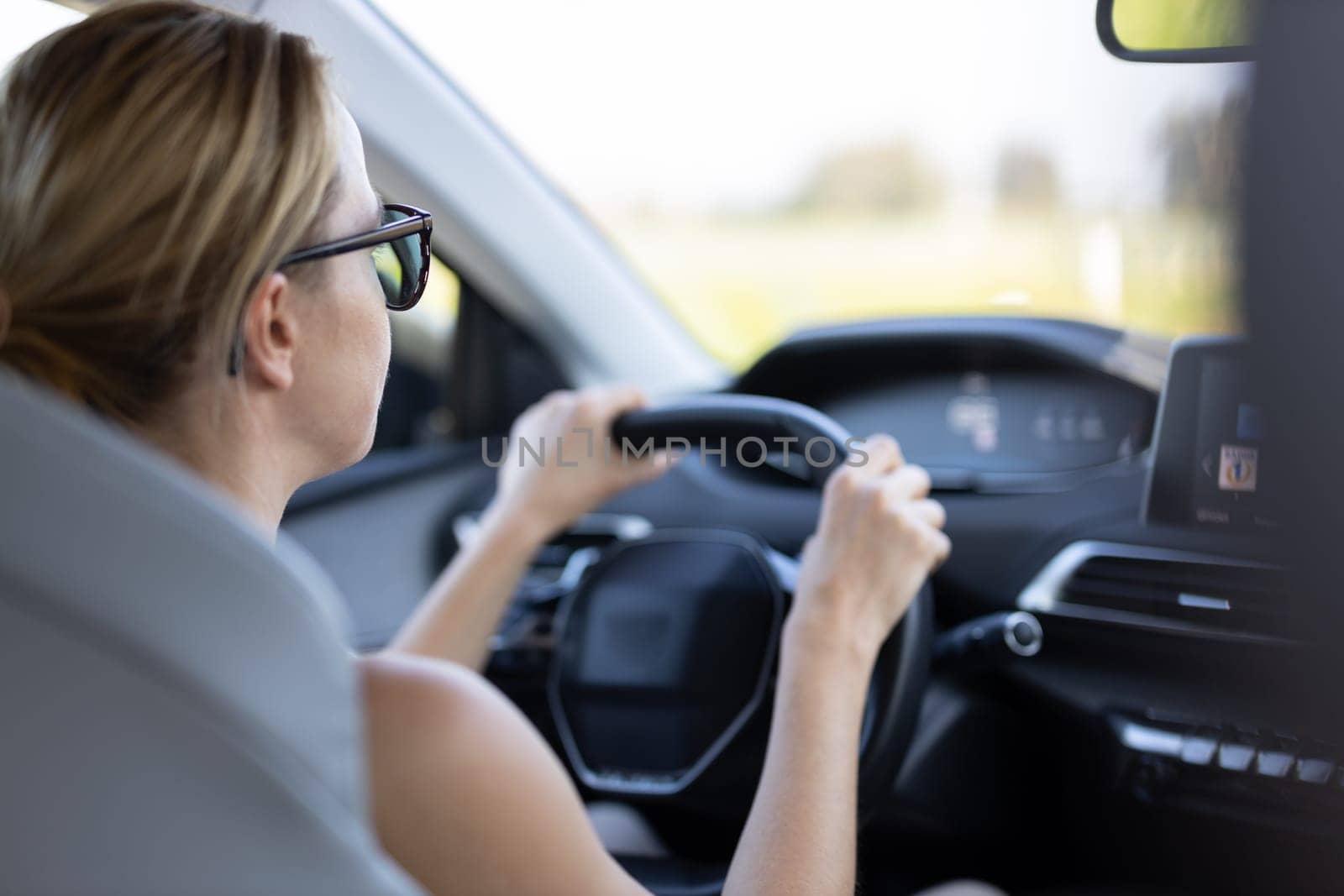 Business woman driving a car to work. Female driver steering car on the road.