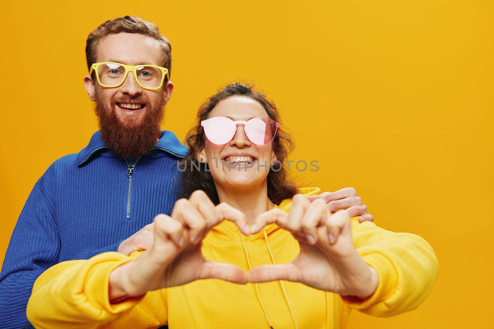 Man and woman couple smiling cheerfully and crooked with glasses, on yellow background, symbols signs and hand gestures, family shoot, newlyweds. by SHOTPRIME