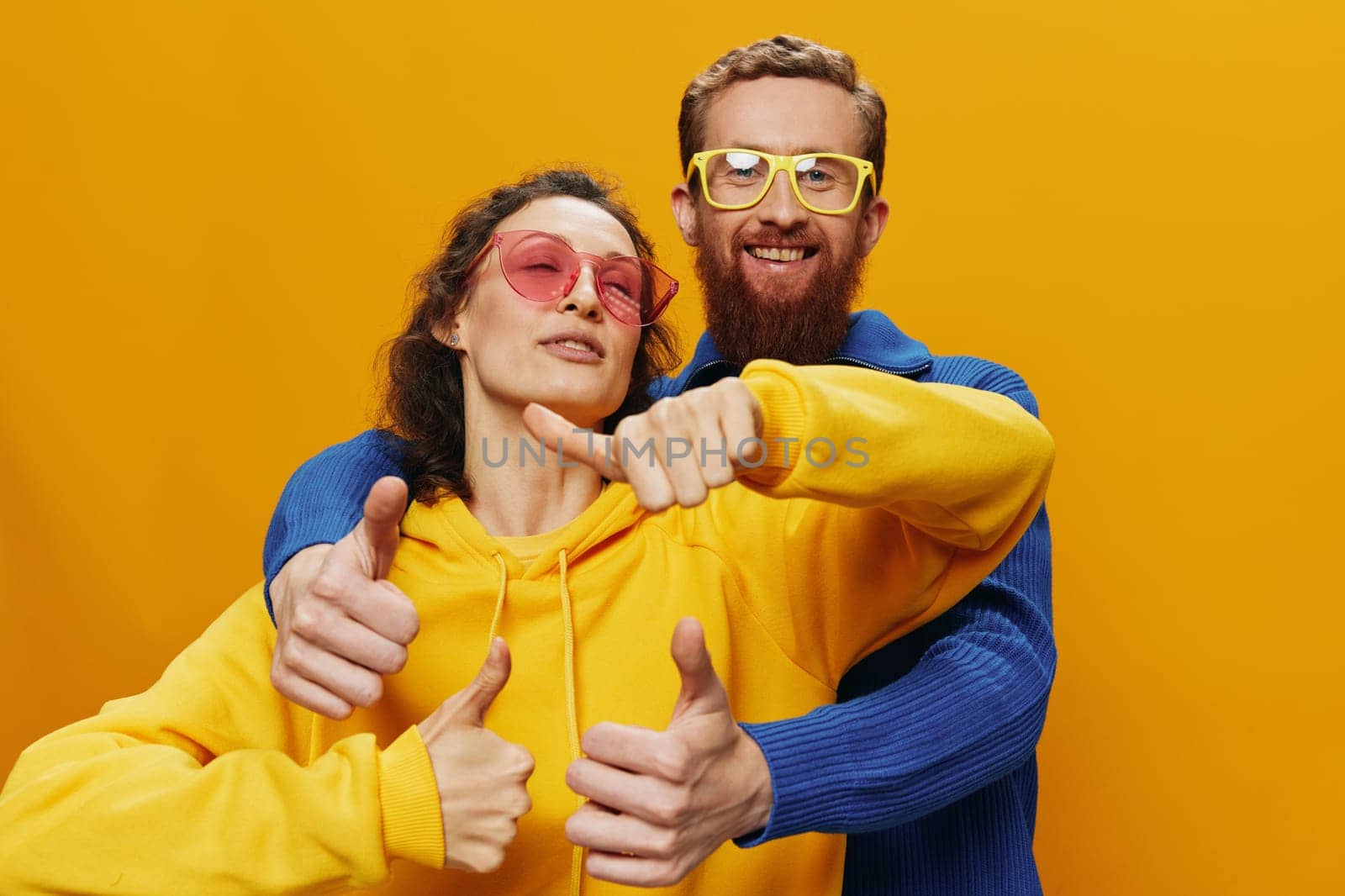 Man and woman couple smiling cheerfully and crooked with glasses, on yellow background, symbols signs and hand gestures, family shoot, newlyweds. High quality photo