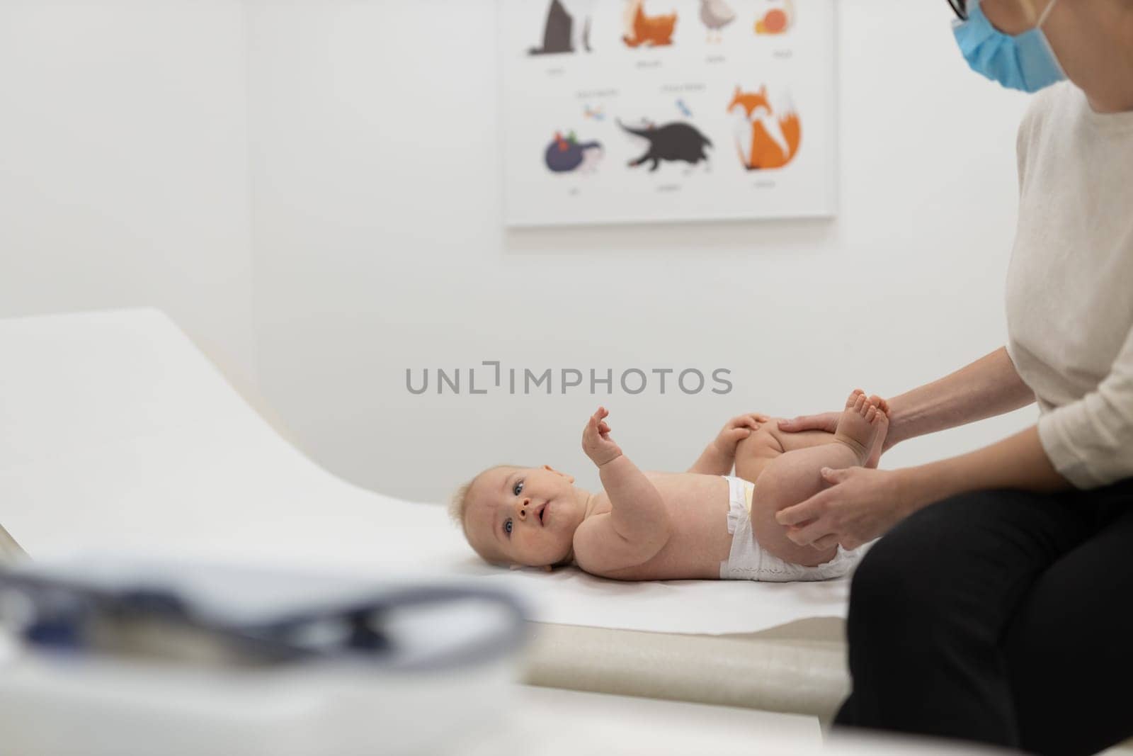 Baby lying on his back during a standard medical checkup at pediatrician by kasto