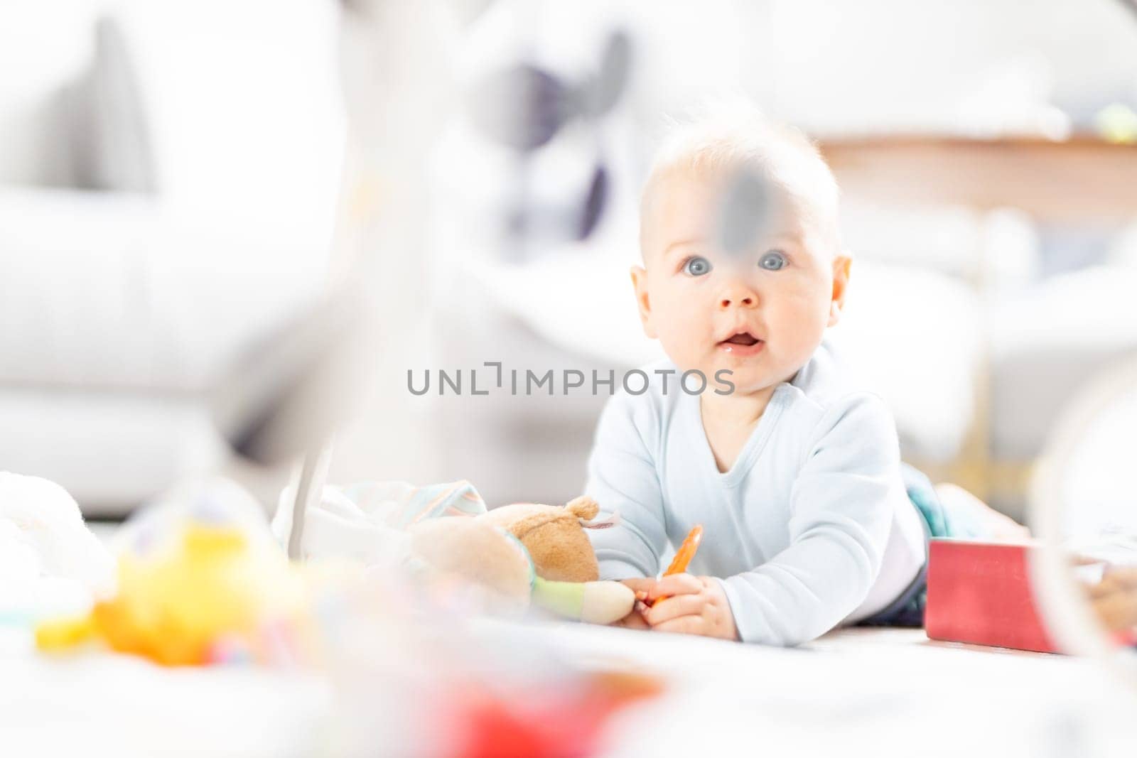Cute baby boy playing with hanging toys arch on mat at home Baby activity and play center for early infant development. Baby playing at home by kasto