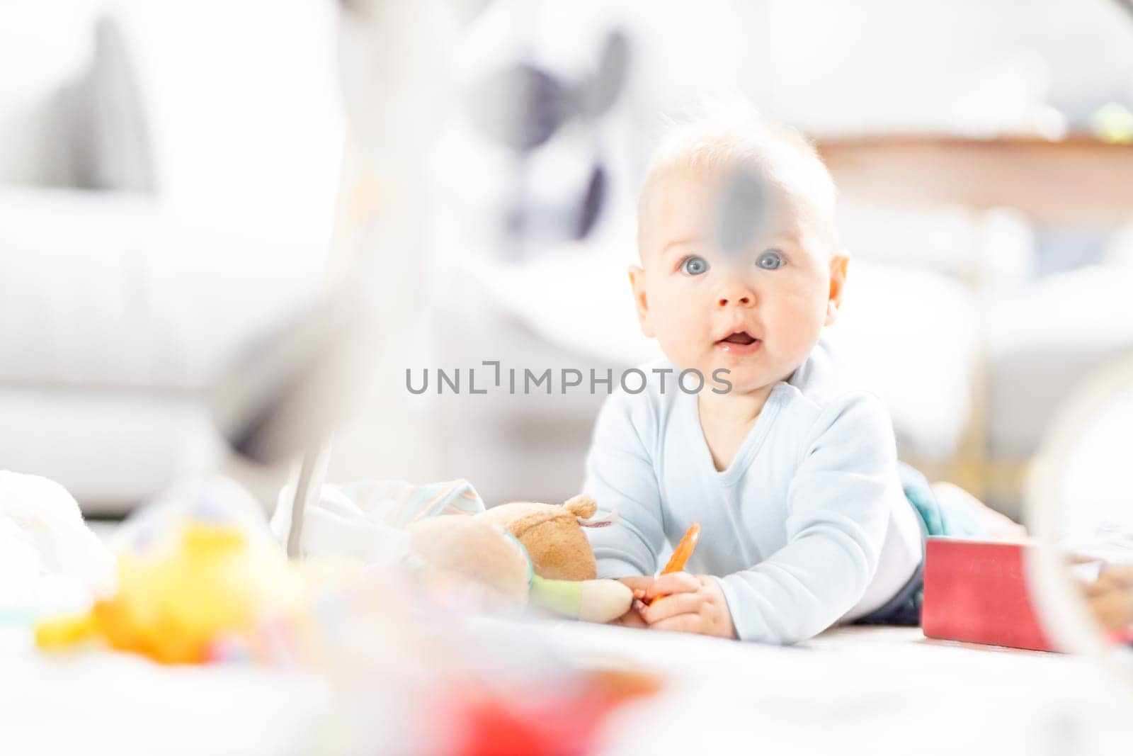 Cute baby boy playing with hanging toys arch on mat at home Baby activity and play center for early infant development. Baby playing at home.