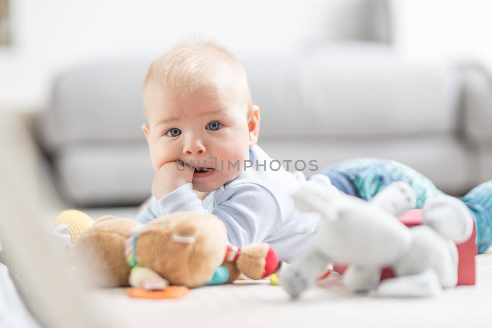 Cute baby boy playing with hanging toys arch on mat at home Baby activity and play center for early infant development. Baby playing at home.