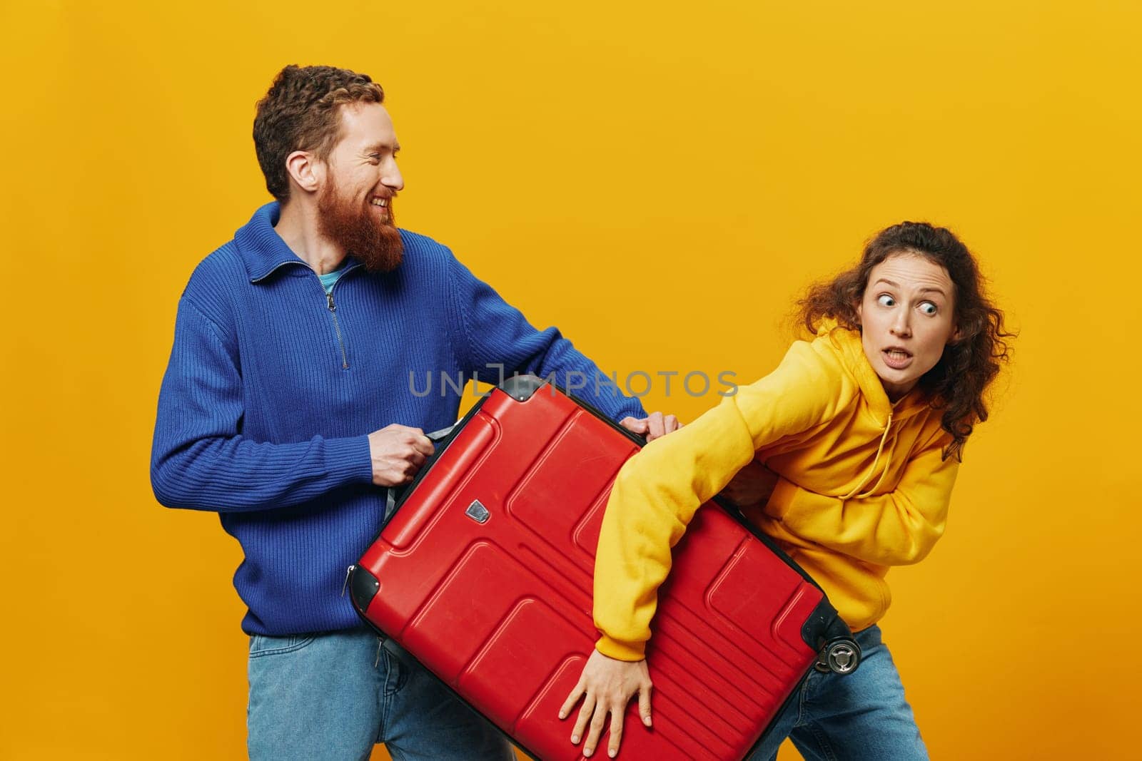 Woman and man smiling, suitcases in hand with yellow and red suitcase smiling merrily and crooked, yellow background, going on a trip, family vacation trip, newlyweds. High quality photo