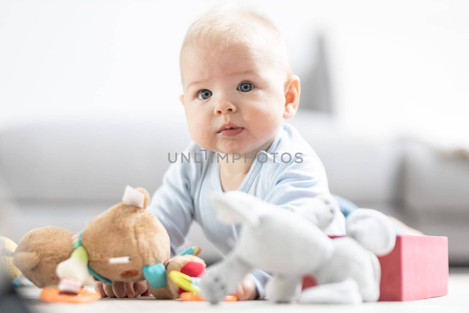 Cute baby boy playing with toys on mat at home Baby activity and play center for early infant development. Baby playing at home