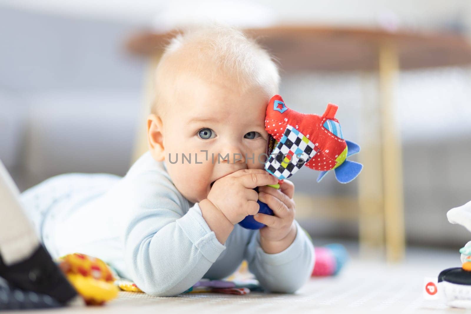 Cute baby boy playing with hanging toys arch on mat at home Baby activity and play center for early infant development. Baby playing at home.