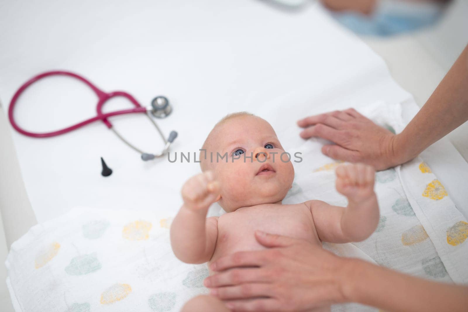 Baby lying on his back as his doctor examines him during a standard medical checkup by kasto