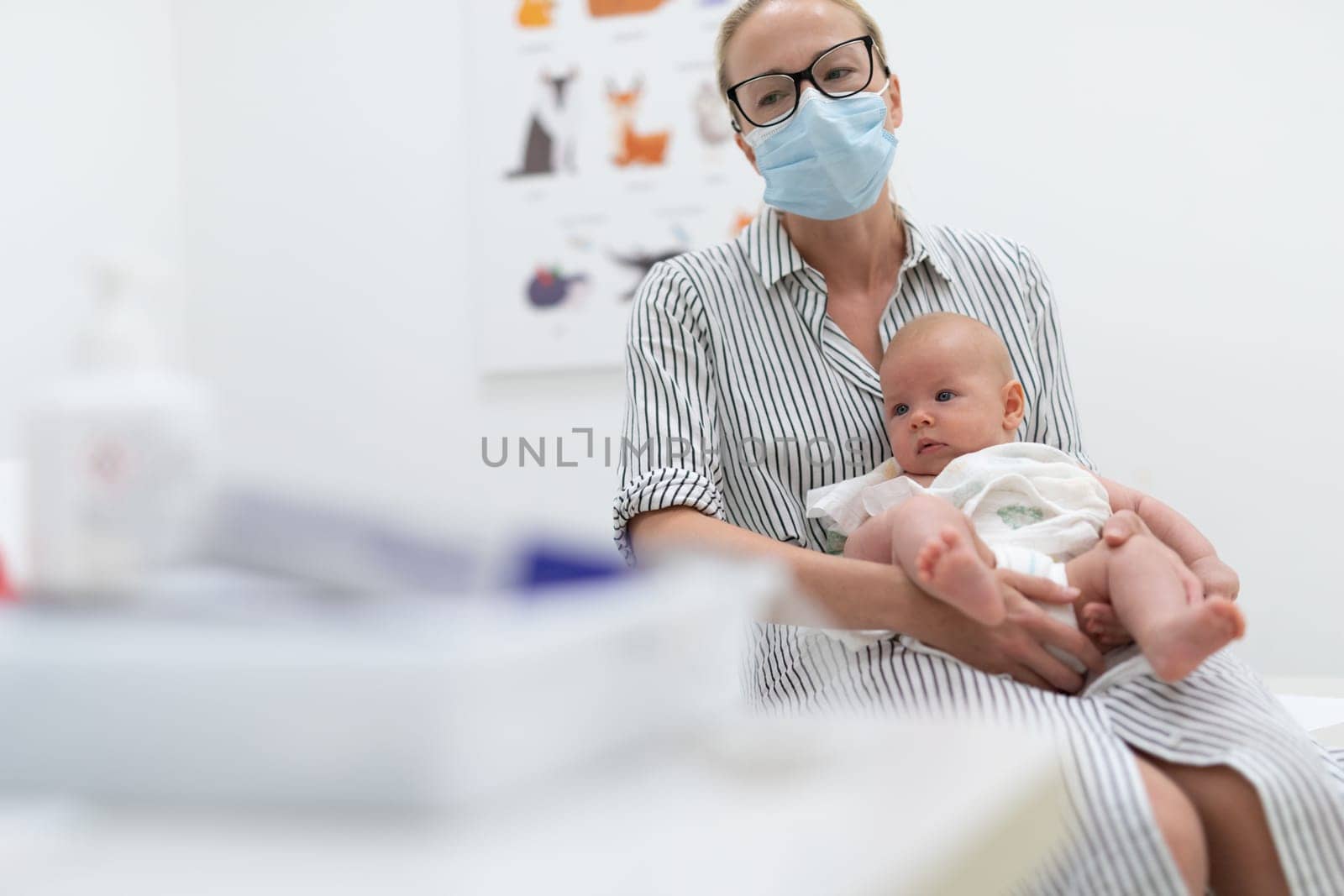 Mother holding her baby boy at medical appointment at pediatrician office