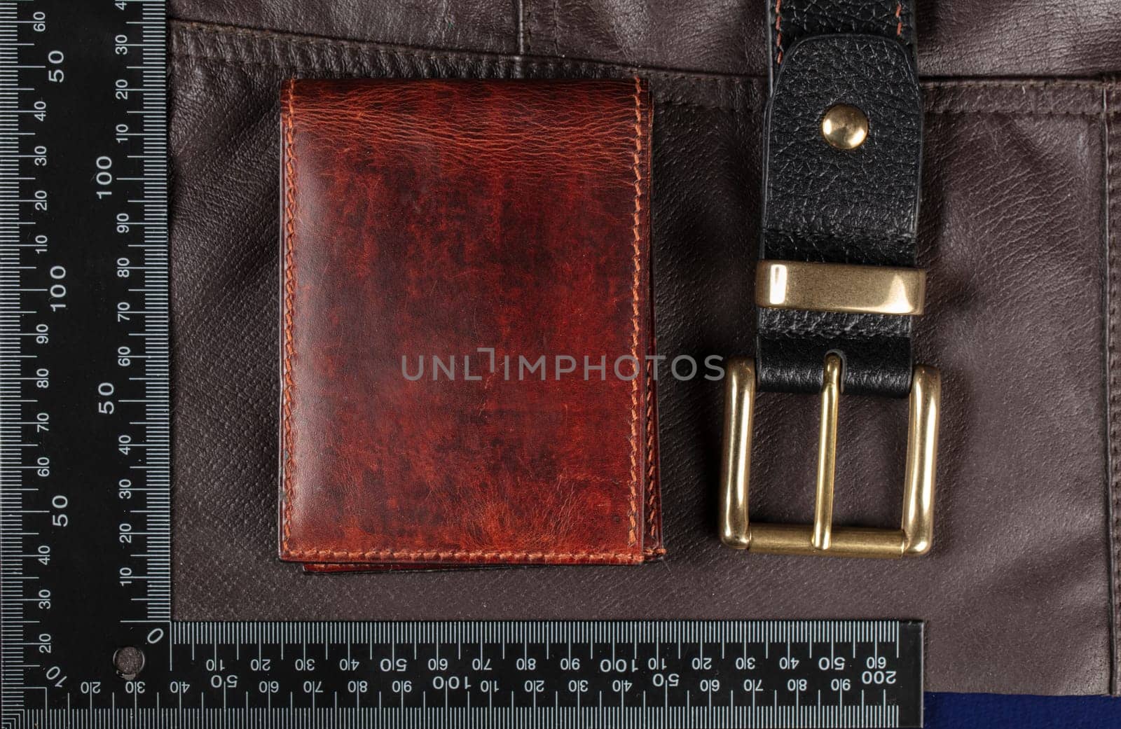 Leather goods purse and belt against the background of a ruler for cutting and sewing.