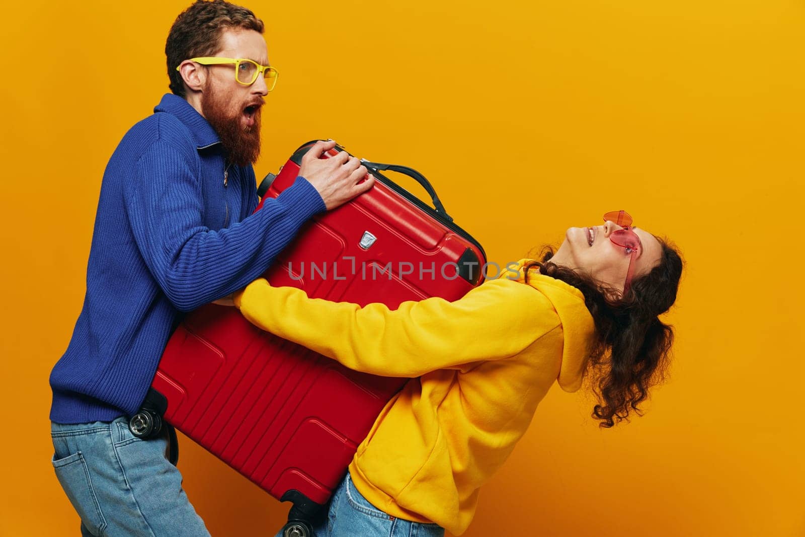 Woman and man smiling, suitcases in hand with yellow and red suitcase smiling merrily and crooked, yellow background, going on a trip, family vacation trip, newlyweds. by SHOTPRIME